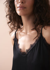 Close up showing lace detail on neckline of black satin camisole