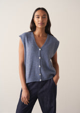 Woman wearing a blue sleeveless knitted waistcoat with blue trousers