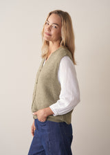 Woman wearing khaki green sleeveless knit waistcoat with blue jeans