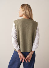Woman wearing khaki green sleeveless knit waistcoat with blue jeans