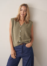 Woman wearing khaki green sleeveless knit waistcoat with blue jeans