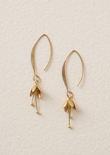 Gold blossom drop earrings on a beige background