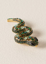 Sparkling snake brooch with twinkling green crystals on a classic pin fastening, photographed on a beige background