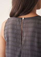 Woman wearing a long, dark gray dress with textured stripes against a plain background