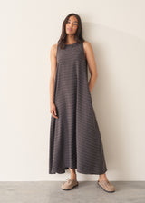 Woman wearing a long, dark gray dress with textured stripes against a plain background
