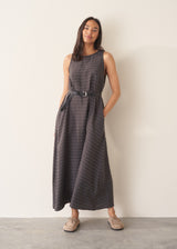 Woman wearing a long, dark gray dress with textured stripes against a plain background