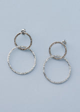Hammered silver drop earrings with interlocking double hoops on blue background