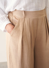 Woman wearing light beige cropped wide leg trousers, matching beige jacket and a white top.