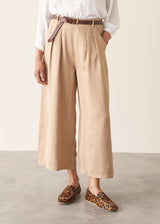 Woman wearing light beige cropped wide leg trousers, matching beige jacket and a white top.