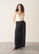 Woman wearing black wide leg trousers with nude camisole and light cardigan