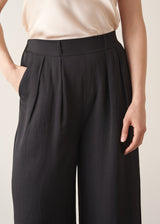 Woman wearing black wide leg trousers with nude camisole and light cardigan