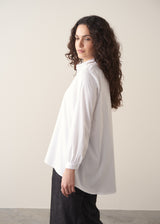 Woman wearing an oversized white shirt and dark jeans