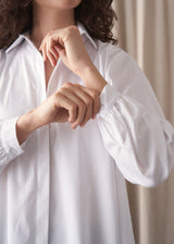 Woman wearing a white oversized shirt, showing close up of buttoned cuff detail