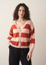 Woman wearing a red and blush pink striped cardigan with black trousers