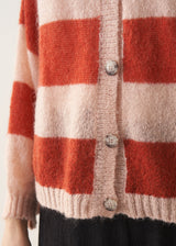 Woman wearing a red and blush pink striped cardigan with black trousers