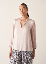 Woman wearing oyster pink satin blouse with leopard print trousers