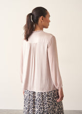 Woman wearing oyster pink satin blouse with leopard print trousers