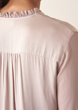 Woman wearing oyster pink satin blouse with leopard print trousers