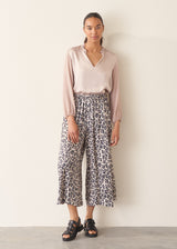 Woman wearing oyster pink satin blouse with leopard print trousers