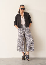 Woman wearing oyster pink satin blouse with leopard print trousers