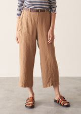 Woman wearing brown straight-leg ankle length linen trousers with a stripe breton top