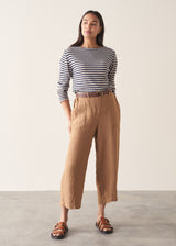 Woman wearing brown straight-leg ankle length linen trousers with a stripe breton top