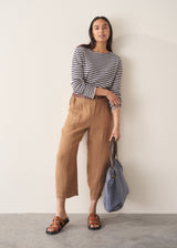 Woman wearing brown straight-leg ankle length linen trousers with a stripe breton top