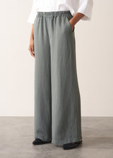 Woman wearing a white shirt with grey wide leg, full length linen blend trousers and kitten heels
