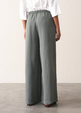 Woman wearing a white shirt with grey wide leg, full length linen blend trousers and kitten heels