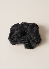 Black hair scrunchie with glittery texture on a beige background