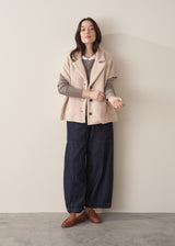 Woman wearing an oatmeal boucle gilet with a grey sweater and blue jeans