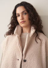 Woman wearing a beige boucle gilet over oatmeal sweater