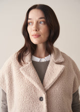 Woman wearing an oatmeal boucle gilet with a grey sweater and blue jeans