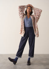 Woman wearing a multicoloured oversized cardigan and jeans against a plain background