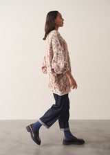 Woman wearing a multicoloured oversized cardigan and jeans against a plain background