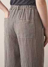 Woman modelling grey checked cropped linen barrel leg trousers with a grey vest top