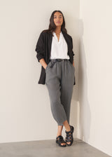 Woman wearing blue and green checked linen barrel leg trousers and a white top.