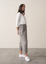 Woman wearing cotton seersucker checked barrel leg trousers and a white top.