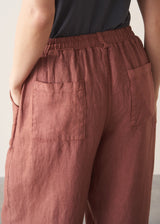 Brown terracotta cropped barrel-leg trousers worn by a person on a neutral background