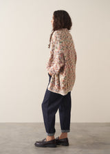 Woman wearing a space dye patterned oversized cardigan and blue jeans against a plain background