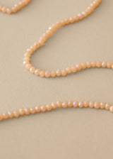 Close up of long nude beaded necklace on beige background