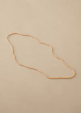 Long nude beaded necklace on beige background