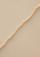 Close up of long nude beaded necklace on beige background