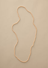 Long nude beaded necklace on beige background