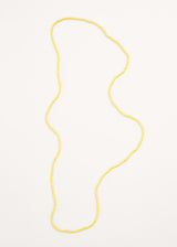 A long yellow crystal necklace on beige background