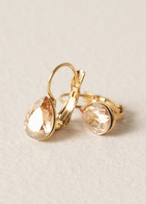 Gold hoop earrings with champagne crystals on a beige background