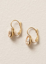 Gold hoop earrings with champagne teardrop crystals on a beige background