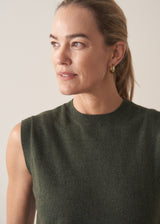 Woman wearing dark green fine knit sweater with removable heart brooch with white barrel leg jeans