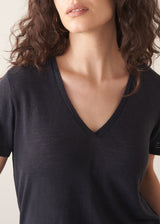 Woman wearing dark grey linen v-neck t-shirt and white jeans