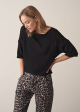 Woman wearing black short sleeve fine knit sweater and leopard print trousers